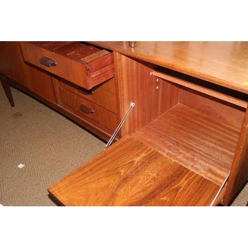 502 - A 1960s teak sideboard, fitted drop front cocktail cabinet, four drawers and cupboards, on tapering ... 