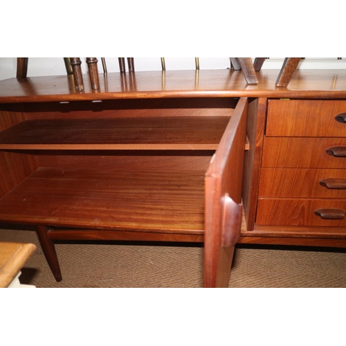 502 - A 1960s teak sideboard, fitted drop front cocktail cabinet, four drawers and cupboards, on tapering ... 