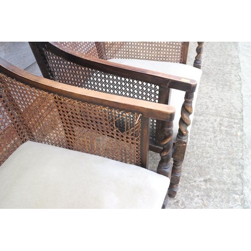 510 - A pair of 1920s polished as walnut bergere armchairs with padded seats, on barley twist stretchered ... 