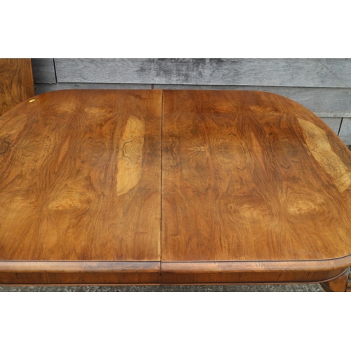 561 - A walnut extending dining table with one extra leaf, on shell carved cabriole supports, 70