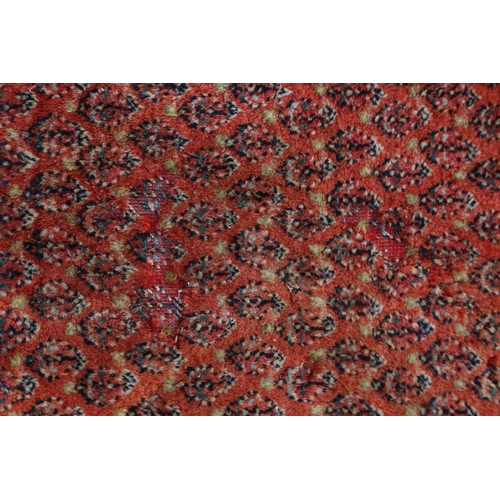 584 - A Persian carpet with all-over boteh design on a red ground, multi-bordered in shades of blue, red, ... 