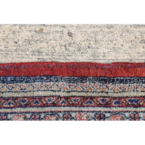 584 - A Persian carpet with all-over boteh design on a red ground, multi-bordered in shades of blue, red, ... 