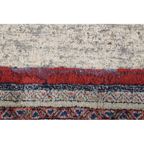 584 - A Persian carpet with all-over boteh design on a red ground, multi-bordered in shades of blue, red, ... 