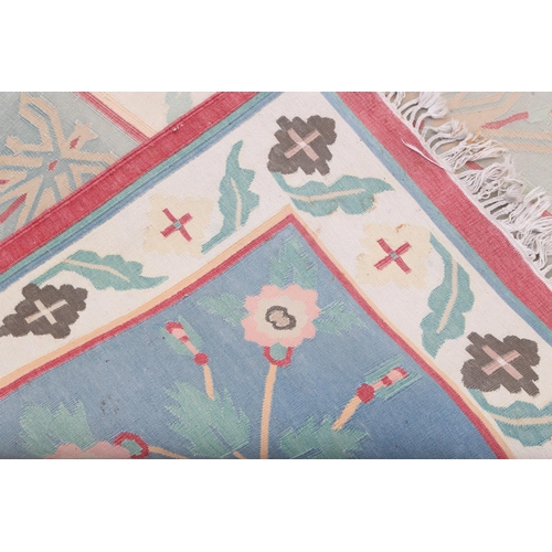 587 - A flat weave carpet of geometric design, in faded shades of blue, pink, green and neutral, 169