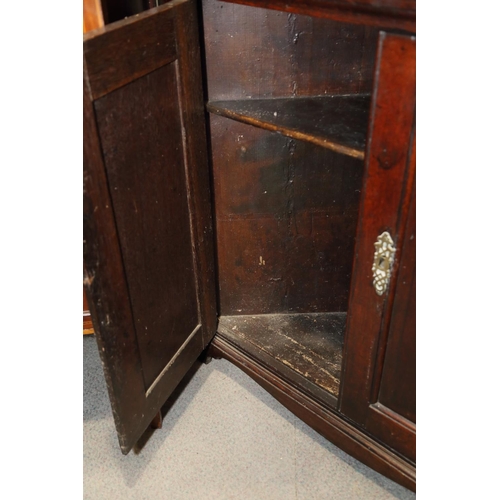 417 - A Georgian oak corner cupboard the upper section with shaped shelves enclosed two arch top panel doo... 