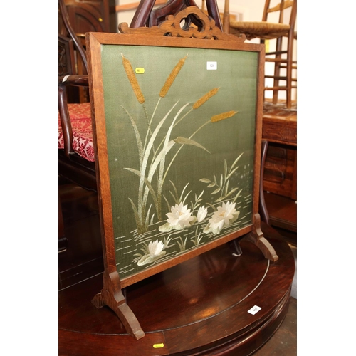 524 - An oak framed firescreen, inset glazed embroidered panel of water plants