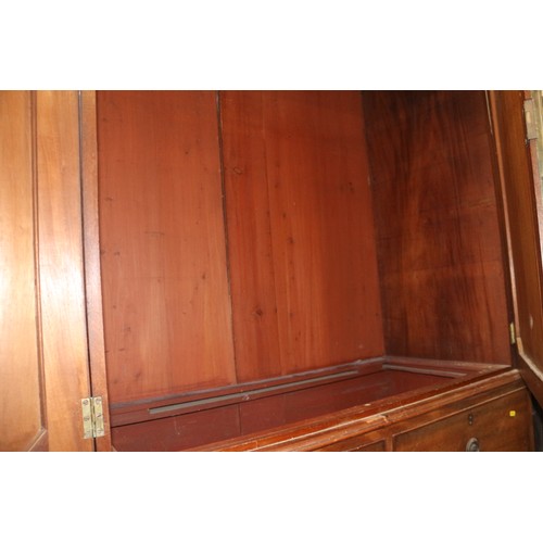 411 - An early 19th century mahogany linen press, the upper section enclosed two doors, over two faux draw... 