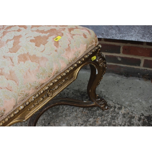 407 - A carved giltwood stool, upholstered in a floral swag pattern fabric, on cabriole supports united by... 