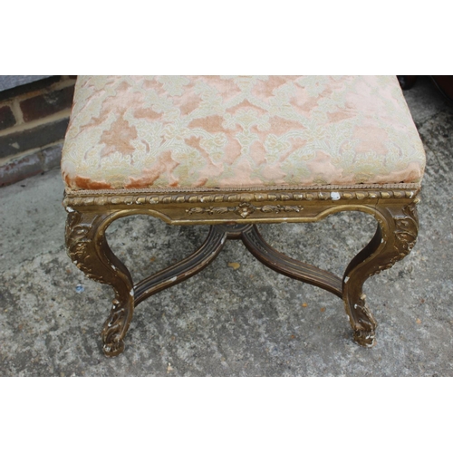 407 - A carved giltwood stool, upholstered in a floral swag pattern fabric, on cabriole supports united by... 