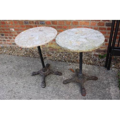 619 - A pair of mottled marble circular topped bistro tables, on cast iron supports, 19