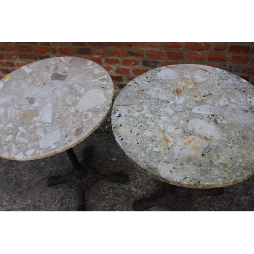 619 - A pair of mottled marble circular topped bistro tables, on cast iron supports, 19