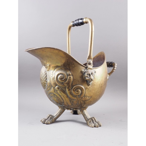 128 - A late 19th century brass coal scuttle with embossed decoration, on three paw supports, 13 1/2