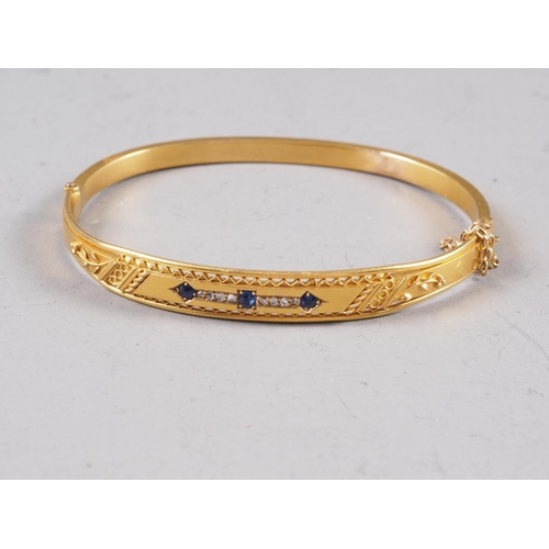 257 - A Victorian gilded 15ct gold hinged bangle, set three sapphires and eight diamonds