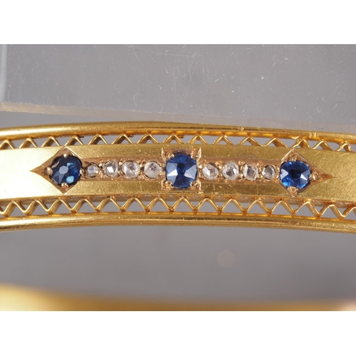 257 - A Victorian gilded 15ct gold hinged bangle, set three sapphires and eight diamonds