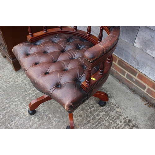 490 - A polished as mahogany spindle back desk elbow chair, button upholstered in a brown leather, on quad... 