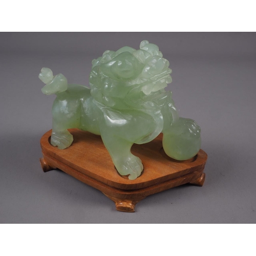 92 - A Chinese carved green jade model of a Dog of Fo, on hardwood stand, 3 1/2