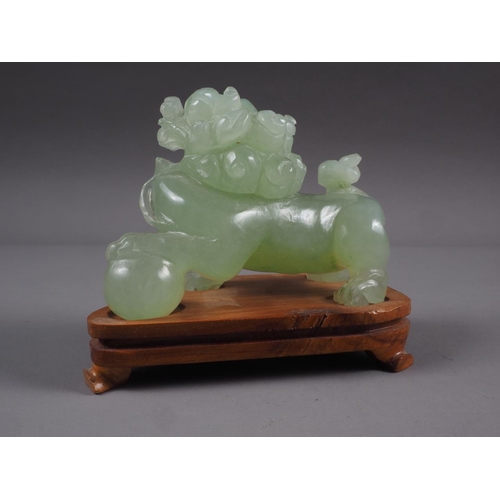 92 - A Chinese carved green jade model of a Dog of Fo, on hardwood stand, 3 1/2