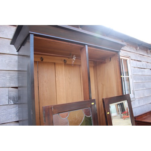 475 - An early 20th century walnut wardrobe enclosed leaded glazed door and mirror panel drawer over one d... 