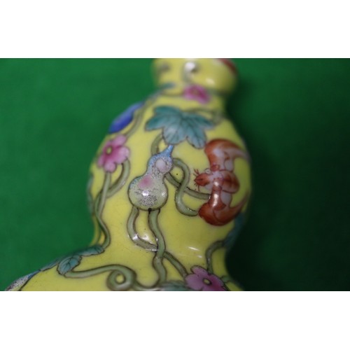 76 - A Chinese double gourd snuff bottle, decorated bats, fruits and flowers, on a yellow ground with sea... 