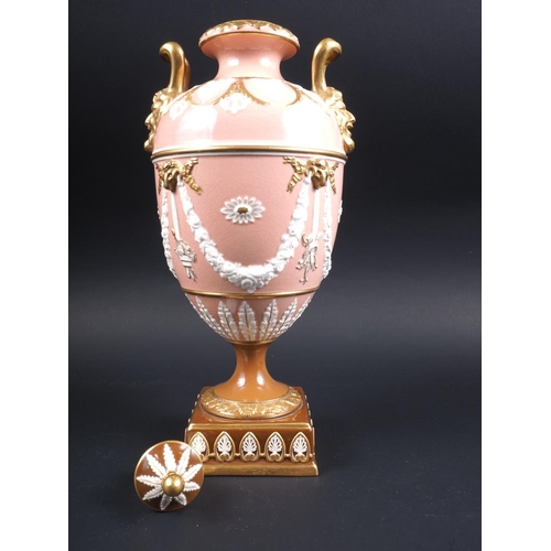 10 - A Wedgwood urn and cover with twin gilt mask handles and relief swag decoration, on a pink ground an... 