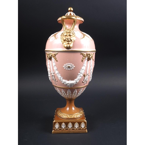 10 - A Wedgwood urn and cover with twin gilt mask handles and relief swag decoration, on a pink ground an... 