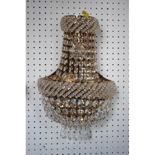 196 - A pair of shaped cut glass wall lights with gilt metal backs and spearpoint drops, 16” high