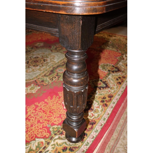 563 - An Edwardian oak extending dining table with four extra leaves, on bulbous turned and carved support... 