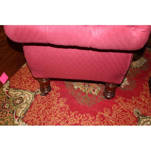 565 - An early 20th century chaise-longue, button upholstered in a red fabric, on turned and castored supp... 