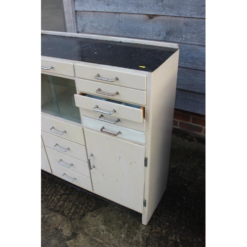 580 - A dentist's instrument cabinet with black glass top, fitted fifteen drawers, central glazed cupboard... 