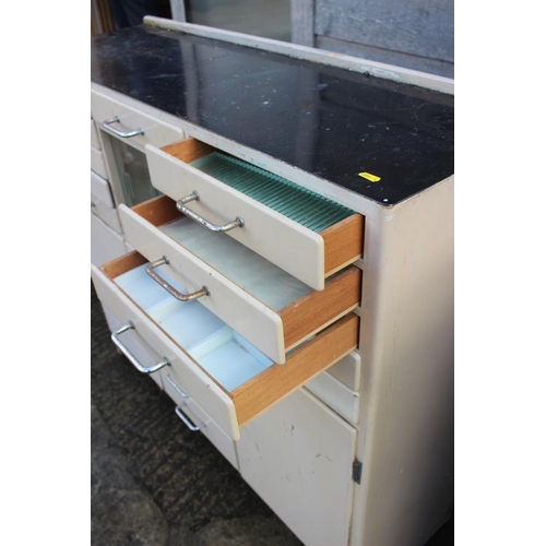 580 - A dentist's instrument cabinet with black glass top, fitted fifteen drawers, central glazed cupboard... 