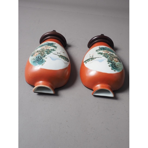 113 - A pair of Chinese wall pockets, formed as vases, decorated panels with landscapes on an orange groun... 