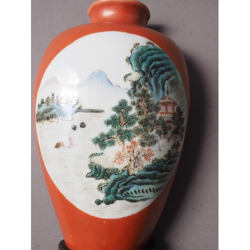 113 - A pair of Chinese wall pockets, formed as vases, decorated panels with landscapes on an orange groun... 