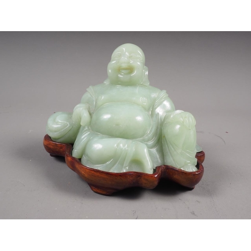 139 - A Chinese green jade figure of Buddha, on hardwood stand, 3 1/2