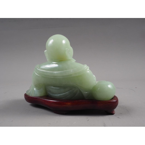 139 - A Chinese green jade figure of Buddha, on hardwood stand, 3 1/2