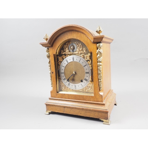 159 - An oak cased arch topped mantel clock with silvered and gilt dial, Roman numerals, gilt finials and ... 