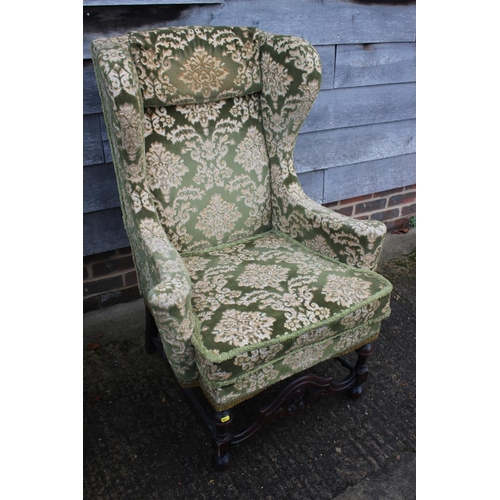 509 - A 17th century style wing armchair, upholstered in a green brocade