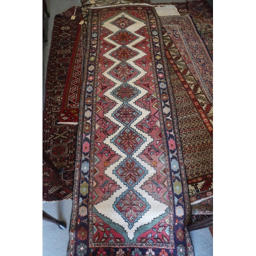 579 - A Kazak style rug with nine star diamond lozenges on a cream ground with pink edges and blue floral ... 