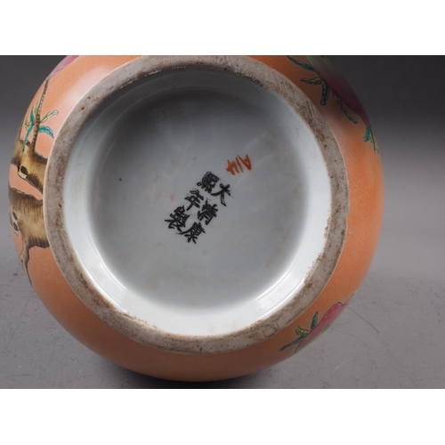 115 - A Chinese bulbous vase with peach and flower decoration on an orange ground and six-character mark t... 