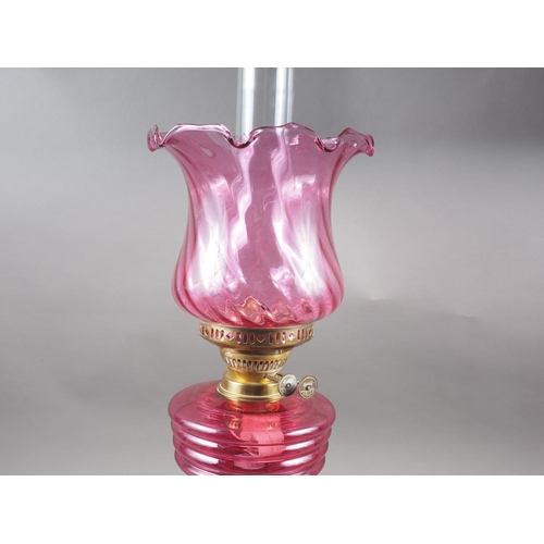 265 - A Victorian oil lamp with pink glass shade and reservoir, on fluted column and circular base, 23 1/4... 