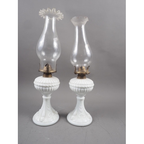 269 - A pair of relief decorated milk glass oil lamps with chimneys