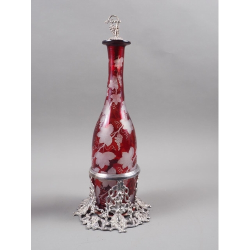 288 - A ruby flashed and vine leaf edged decanter, on silver plated vine leaf stand with matching stopper,... 