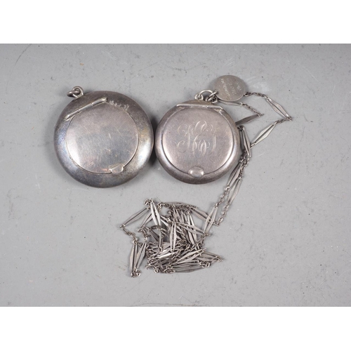 310 - A silver powder compact, on chain, and a similar larger