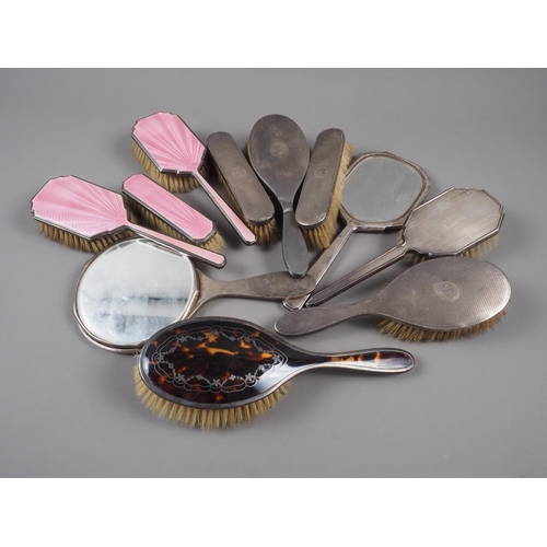 324 - A pink enamelled four-piece dressing table set (damages), five silver mounted brushes and a similar ... 