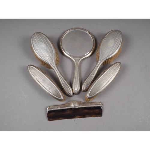 327 - A silver backed dressing table set, comprising four brushes, a comb and a hand mirror