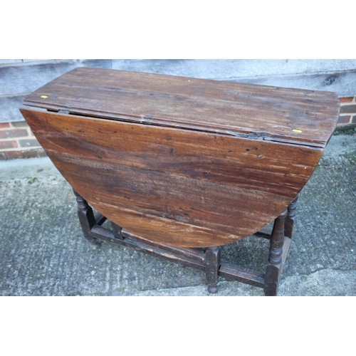 494 - An oak oval drop leaf dining table, on turned and stretchered gate leg supports, 43