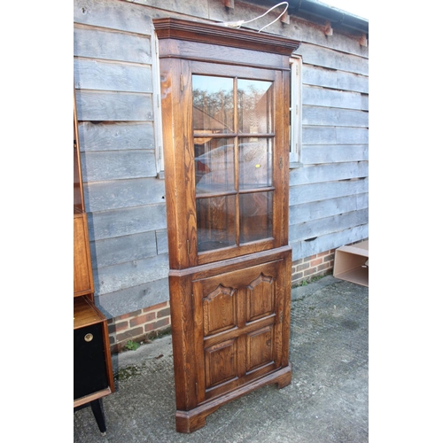 499 - An oak corner display cabinet, the upper section enclosed lattice glazed door over ogee arch panelle... 