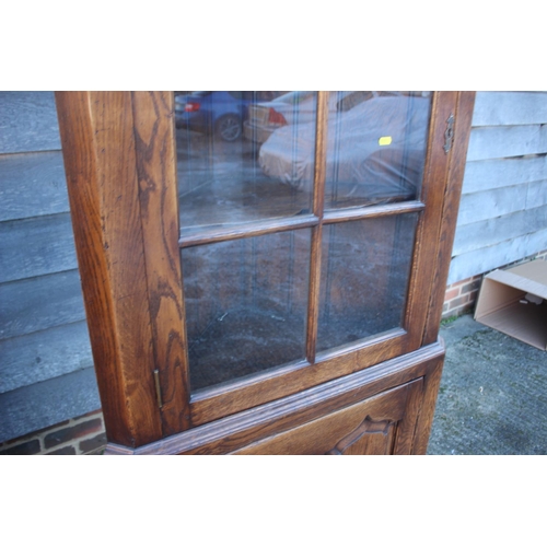 499 - An oak corner display cabinet, the upper section enclosed lattice glazed door over ogee arch panelle... 