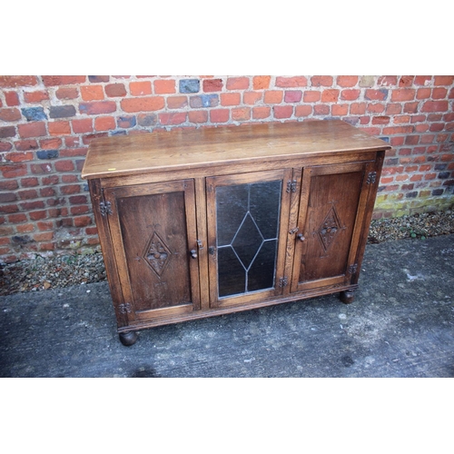 524 - An oak display cabinet enclosed leaded glazed door and two panelled door, on bun feet, 46