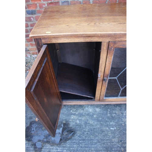 524 - An oak display cabinet enclosed leaded glazed door and two panelled door, on bun feet, 46