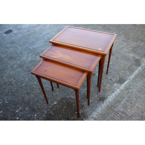 527 - A nest of three yew occasional tables, on turned supports, 23